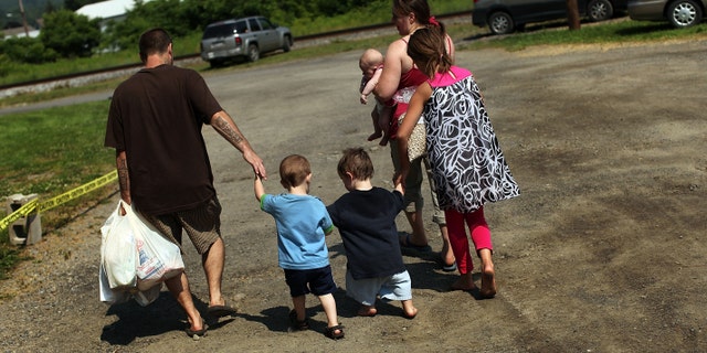 OSWEGO, NY - JUNE 20: Members of the Dolan family walk home with bags of food after a food distribution by the Food Bank of the Southern Tier Mobile Food Pantry on June 20, 2012 in Oswego, New York. The mobile food pantry program was introduced in 2007 in the Southern Tier of New York and covers nearly 4,000 predominately rural miles. The converted beverage truck delivers fresh produce, dairy products and other grocery items to individuals and families in need. The pantry typically distributes for a period of two hours and provides 100 to 160 families with food. According to the 2010 Census, 15.72% the population serviced by the mobile pantry live at or below the federal poverty level. According to statistics presented at a recent U.S. Senate committee hearing, almost one in seven Americans are living below the poverty line with a significant number of them being children. (Photo by Spencer Platt/Getty Images)