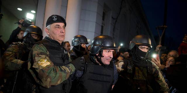 Former Public Works Secretary Jose Lopez, center, is escort by police outside the police station in the outskirts of Buenos Aires, Argentina, Tuesday, June 14, 2016. Lopez, an official in the former government of President Fernandez was arrested on Tuesday while trying to hide millions in cash and jewels in a monastery, captivating Argentina in what the cabinet chief said seems more like the plot of a Hollywood movie. (AP Photo/Natacha Pisarenko)