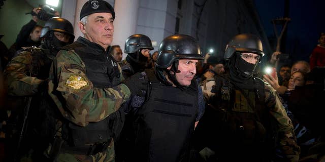 Former Public Works Secretary Jose Lopez, center, is escort by police outside the police station in the outskirts of Buenos Aires, Argentina, Tuesday, June 14, 2016. Lopez, an official in the former government of President Fernandez was arrested on Tuesday while trying to hide millions in cash and jewels in a monastery, captivating Argentina in what the cabinet chief said seems more like the plot of a Hollywood movie. (AP Photo/Natacha Pisarenko)