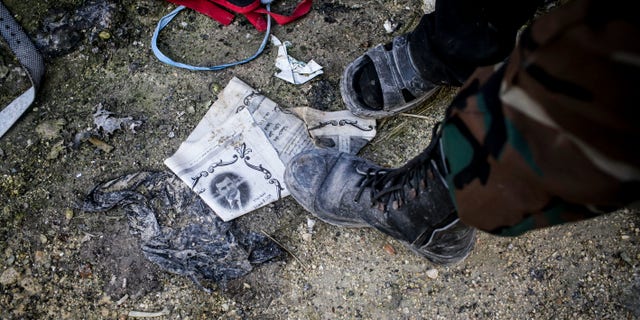 A Free Syrian Army fighter steps on a paper with the photo of Syrian President Bashar Assad in Aleppo, Syria, Tuesday, Jan. 15, 2013. Two explosions struck the main university in the northern Syrian city of Aleppo on Tuesday, causing an unknown number of casualties, state media and anti-government activists said. (AP Photo/Andoni Lubaki)