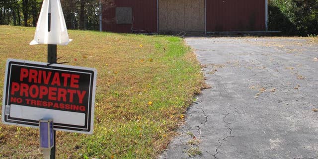 In this Tuesday, Oct. 18, 2016 photo, a private property sign guards the boarded up garage on property on Dana Rhoden and her children, Chris Rhoden Jr., and Hanna Rhoden, were found on April 22 in Piketon, Ohio.