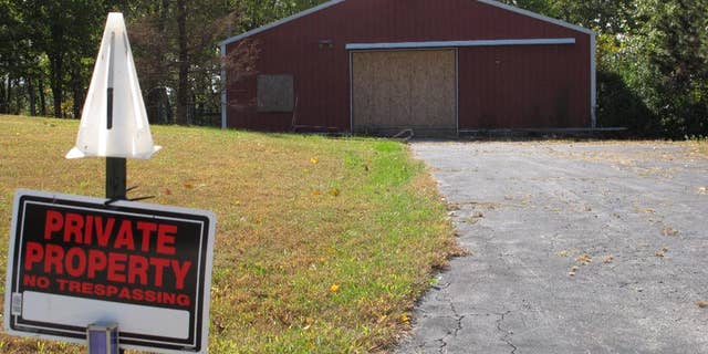 In this Tuesday, Oct. 18, 2016 photo, a private property sign guards the boarded up garage on property on Union Hill Road near the trailer where the bodies of Dana Rhoden and her children, Chris Rhoden Jr., and Hanna Rhoden, were found on April 22 in Piketon, Ohio.