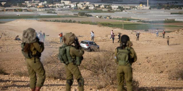 Palestinians and Israeli activists run away from a tear gas fired by Israeli soldiers during a demonstration against the construction of Jewish settlements in the Jordan Valley, in the West Bank, Thursday, Nov. 17, 2016. (AP Photo/Majdi Mohammed)