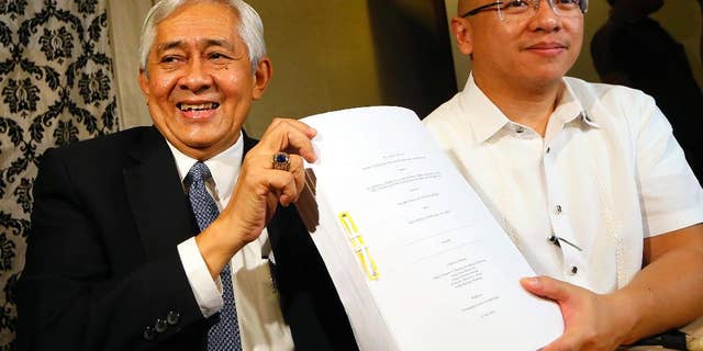 Associate Justice of the Supreme Court Francis Jardeleza, left, and former Solicitor General Florin Hilbay hold a photocopy of the Hague-based U.N. international arbitration tribunal ruling favoring the Philippines in its case against China on the dispute on South China Sea following a news conference Wednesday, July 13, 2016 in Manila, Philippines. The Permanent Court of Arbitration (PCA) issued its ruling Tuesday in The Hague in response to an arbitration case brought by the Philippines against China regarding the South China Sea, saying that any historic rights to resources that China may have had were wiped out if they are incompatible with exclusive economic zones established under a U.N. treaty. Jardeleza and Hilbay were members of the Philippine team who filed the case against China in The Hague. (AP Photo/Bullit Marquez)