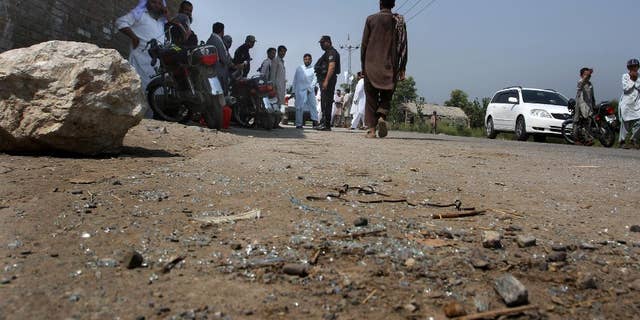 Pakistani police officers and local residents gather at the site of firing incident at Garhi Sohbat Khan on the outskirts of Peshawar, Pakistan, Sunday, Sept. 18, 2016. Two gunmen on a motorcycle killed three soldiers Sunday, police said. (AP Photo/Mohammad Sajjad)