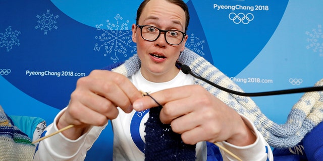 Antti Koskinen, snowboard head coach, shows how he knits, during a news conference in Pyeongchang, South Korea, February 14, 2018.