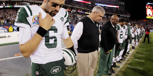 New York Jets quarterback Mark Sanchez (6) and head coach Rex Ryan bow their heads during a moment of silence for the victims of the Sandy Hook Elementary School shootings in Newtown, Conn., before an NFL football game against the Tennessee Titans, Monday, Dec. 17, 2012, in Nashville, Tenn. (AP Photo/Wade Payne)