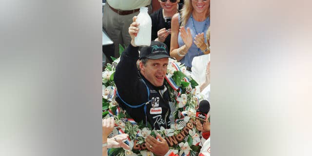 FILE - In this May 24, 1998 file photo, Indianapolis 500 winner Eddie Cheever hoists the traditional bottle of milk after winning the 82nd running of the race, in Indianapolis. (AP Photo/Michael Conroy, File)