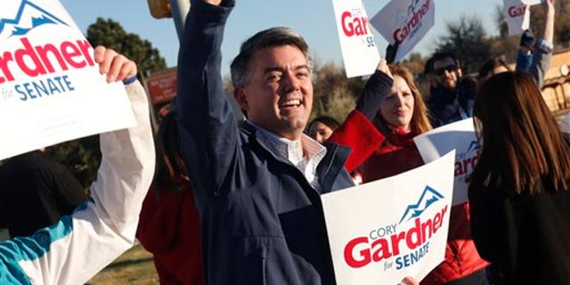 Cory Gardner, Republican candidate for the U.S. Senate seat in Colorado, joins supporters in waving placards on corner of major intersection in south Denver suburb of Centennial, Colo., early on Tuesday, Nov. 4, 2014. Gardner is facing Democratic incumbent U.S. Sen. Mark Udall in a pitched battle for the seat. (AP Photo/David Zalubowski)