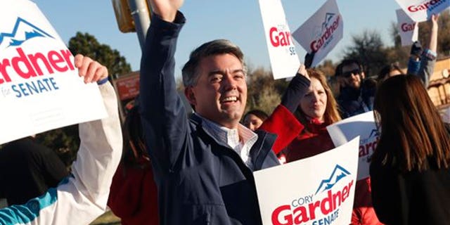 Cory Gardner, Republican candidate for the U.S. Senate seat in Colorado, joins supporters in waving placards on corner of major intersection in south Denver suburb of Centennial, Colo., early on Tuesday, Nov. 4, 2014. Gardner is facing Democratic incumbent U.S. Sen. Mark Udall in a pitched battle for the seat. (AP Photo/David Zalubowski)