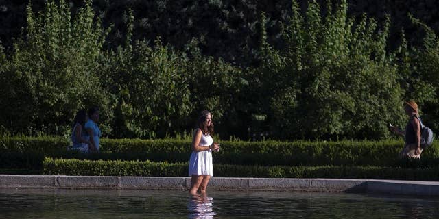 A woman cools off in a park pond in Madrid, Spain, Thursday, July 9, 2015. Spain has been in a heat wave for nearly two weeks, with temperatures reaching 40 C (104 F). The heatwave is expected to last around another week. (AP Photo/Paul White)