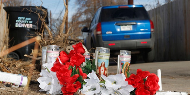 File--In this file photograph taken Tuesday, Jan. 27, 2015, a vehicle passes by the candles and bouquets left near the scene of a fatal police shooting in an alleyway in northeast Denver. A 17-year-old woman was fatally shot by police after she allegedly hit and injured an officer while driving a stolen vehicle early Monday, Jan. 26, in a northeast Denver alleyway. On Friday, June 5, 2015, Denver District Attorney Mitch Morrissey issued a statement saying that the two Denver Police officers involved in the shooting will not face criminal charges. (AP Photo/David Zalubowski, file)