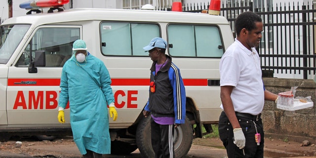 In this photo taken on Monday, Aug. 4, 2014, health workers outside Connaught Hospital, after the arrival of patient with symptoms of the Ebola virus in the city of Freetown, Sierra Leone. The global Ebola outbreak touched American shores more definitively Monday, as Atlanta awaited the arrival of its second Ebola patient by morning, and a New York hospital announced it had isolated a man with possible symptoms who walked into its emergency room.(AP Photo/ Youssouf Bah)