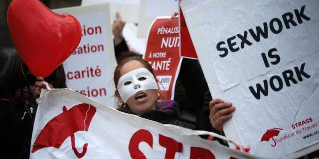 FILE - In this Nov.29, 2013 file photo, a French sex worker demonstrates outside the National Assembly in Paris, France. A French bill aimed at decriminalizing prostitutes and fining their customers is being turned upside down by the Senate, led by the conservative opposition. The proposed bill, aims at introducing a 1,500-euro (about $1,623) fine for customers and decriminalizing the estimated 40,000 prostitutes in France. (AP Photo/Christophe Ena, File)
