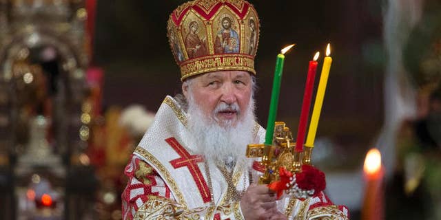 FILE - In this file photo dated Sunday, May 1, 2016, Russian Orthodox Patriarch Kirill holds candles during the Easter service in the Christ the Savior Cathedral in Moscow, Russia. The head of Russia's Orthodox Church, Patriarch Kirill begins a four-day visit to Britain, on upcoming Saturday Oct. 15, 2016, that includes an audience with Britain's Queen Elizabeth II. (AP Photo/Alexander Zemlianichenko, FILE )