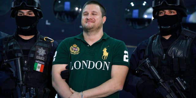 La policía custodia a Edgar Valdez Villareal, alias La Barbie y uno de los presuntos capos del narcotráfico más buscado, durante una rueda de prensa en la ciudad de México, el martes 31 de agosto de 2010. (AP foto/Alexandre Meneghini)