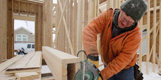 In this Wednesday, Feb. 18, 2015 photo, carpenter Joe Tominc cuts wood for a post on a home under construction in Pepper Pike, Ohio. The Commerce Department reports on U.S. construction spending in January on Monday, March 2, 2015. (AP Photo/Tony Dejak)