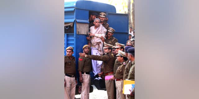 Controversial religious leader Sant Rampal stands by the door of a police van as he is brought to a court, surrounded by police personnel in Chandigarh, India, Thursday, Nov. 20, 2014. Indian police arrested the 63-year-old self-styled Hindu guru at his sprawling ashram in the northern part of the country, ending a days-long standoff in which six people died and hundreds were injured. He is wanted for questioning in a 2006 murder case, but has repeatedly ignored orders to appear in court. (AP Photo/Kapil Sethi)