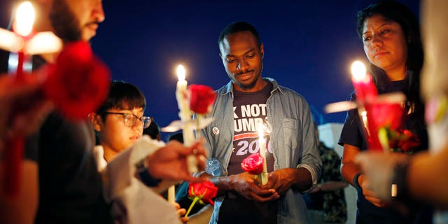 Maurice Forbes, center, holds a candle with others during a vigil at The Center, a community center for the LGBT community, Sunday, June 12, 2016, in Las Vegas. The vigil was for the victims of the Pulse nightclub shooting in Orlando. (AP Photo/John Locher)