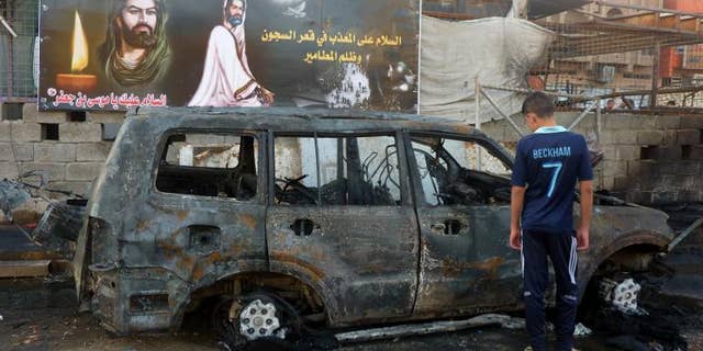 An Iraqi boy inspects a burnt out vehicle the day after a bomb attack in the Sadr City district of Baghdad on September 22, 2103