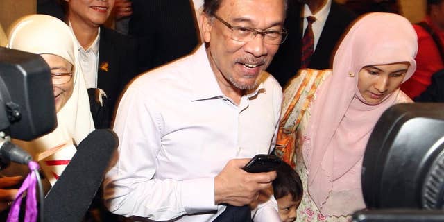 FILE - In this Tuesday, Feb. 10, 2015 file photo, Malaysian opposition leader Anwar Ibrahim, center, arrives at court house in Putrajaya, Malaysia. Less than a week after Anwar was jailed for sodomy, his lawyers said Monday, Feb. 16, he faces a serious health risk, being kept in a bare cell with just a 2-inch-thick foam mattress on the floor, a bucket for bathing and a squat toilet. Anwar began a five-year prison sentence last Tuesday after the country's top court turned down his final appeal, ruling there was overwhelming evidence that he had sodomized a former male aide. (AP Photo/File) MALAYSIA OUT
