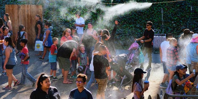 In this Saturday, Sept. 24, 2016 photo, visitors to the Los Angeles County fair cool off under outdoor misters in Pomona, Calif. Californians braced Monday, Sept. 26 for another hot autumn day as forecasters warned of soaring temperatures and potential wildfires due to hot, dry and windy conditions. (AP Photo/Richard Vogel)