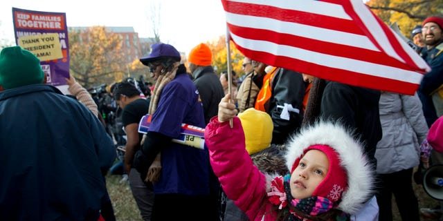 Joselyn Vargas, 7, of Hyattsville, Md., waves a U.S. flag during a rally in Lafayette Park across from the White House in Washington, Friday, Nov. 21, 2014, thanking President Obama for his executive action on illegal immigratio. Vargas' parents are eligible under the executive action as the girl and her younger sister are U.S. citizens. (AP Photo/Jacquelyn Martin)
