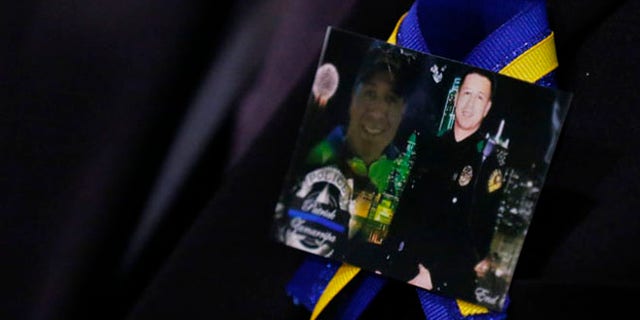 A family member wears a ribbon with photos of Patrick Zamarripa during a funeral service for Dallas police officer Patrick Zamarripa on Saturday, July 16, 2016 at Wilkerson-Greines Athletic Center in Fort Worth, Texas. Zamarripa was one of the five officers killed July 7 by a lone gunman during a march to protest recent fatal shootings of black men in Minnesota and Louisiana by police. (Ashley Landis/The Dallas Morning News via AP, Pool)