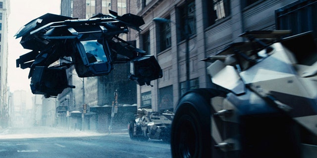 The Bat flying vehicle flies through Gotham's urban canyons in the Dark Knight Rises.