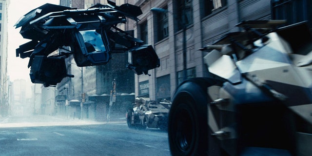 The Bat flying vehicle flies through Gotham's urban canyons in the Dark Knight Rises.