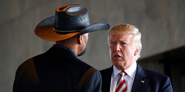 Republican U.S. presidential nominee Donald Trump talks with Milwaukee County Sheriff David Clarke Jr. at the Milwaukee County War Memorial Center in Milwaukee, Wisconsin August 16, 2016. REUTERS/Eric Thayer - S1AETVWQYQAB