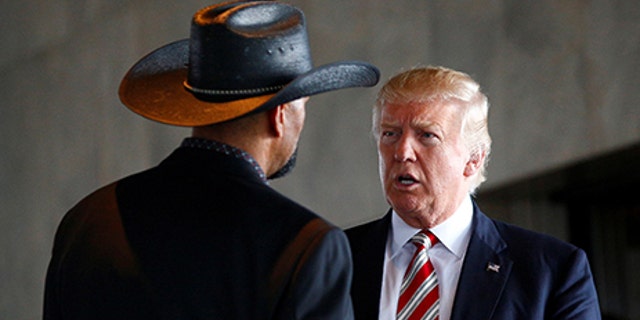 Republican U.S. presidential nominee Donald Trump talks with Milwaukee County Sheriff David Clarke Jr. at the Milwaukee County War Memorial Center in Milwaukee, Wisconsin August 16, 2016. REUTERS/Eric Thayer - S1AETVWQYQAB