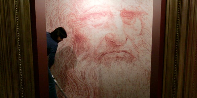 A cleaner vacuums in front of a Leonardo da Vinci self-portrait drawn around 1515 or 1516, during the inauguration of the exhibition