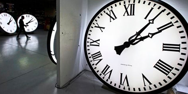 Tom Liberatore, a materials purchasing manager, walks past clocks being tested prior to shipping at the Electric Time Company in Medfield, Mass.