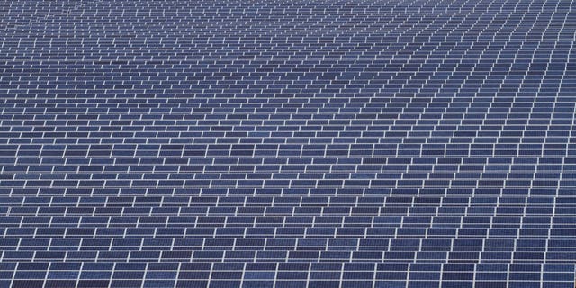 Indian workers walk past solar panels at the Gujarat Solar Park.