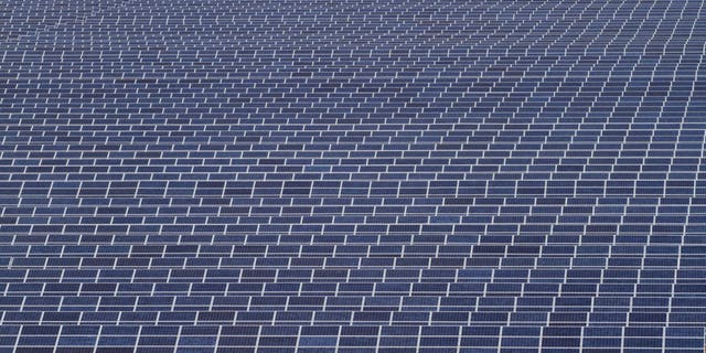 Workers walk past solar panels at the Gujarat Solar Park at Charanka in Patan district, about 155 miles from Ahmadabad, India, on Saturday, April 14, 2012. (AP Photo/Ajit Solanki)