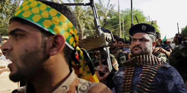 FILE - In this Monday, June 16, 2014 file photo, Shiite tribal fighters raise their weapons and chant slogans against the al-Qaida-inspired Islamic State of Iraq and the Levant, who now call themselves the Islamic State, in Basra, Iraq. Iran and the United States share a common enemy in the Islamic State militant group, but a deep-seated lack of trust has so far kept the longtime foes from publicly joining hands in a coalition to defeat the extremists. Their inability to work together complicates efforts to beat back the extremists that both Washington and Tehran see as a threat, and has left Iraq’s new government - which considers both countries allies - scratching its head as it tries to tackle the most serious threat to its stability since American troops left in 2011. (AP Photo/ Nabil Al-Jurani, File)
