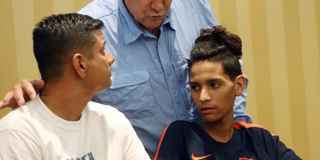 Anthony Borges sits with his father after the lawyer read a statement regarding the attack.