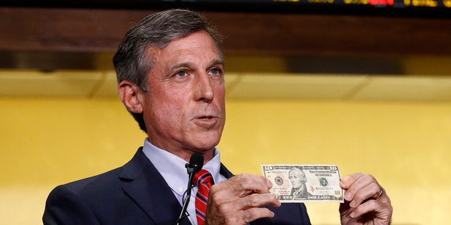 Delaware Gov. John Carney displays a ten dollar bill before using it to place a bet on a baseball game between the Chicago Cubs and the Philadelphia Phillies.