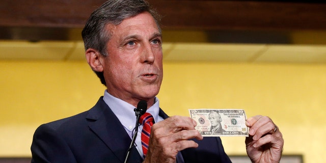 Delaware Gov. John Carney displays a ten dollar bill before using it to place a bet on a baseball game between the Chicago Cubs and the Philadelphia Phillies.