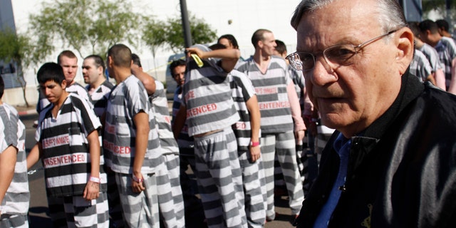PHOENIX, AZ - APRIL 17:   Inmates walk as they are moved after being ordered by Maricopa County Sheriff Officer Joe Arpaio (R), looking on, to be placed into new housing to open up new beds for maximum security inmates on April 17, 2009 in Phoenix, Arizona. Arpaio has been facing criticism from Hispanic activists and lawmakers, alleging that Arpaio's crackdown methods on illegal immigrants involve racial profiling. (Photo by Joshua Lott/Getty Images) *** Local Caption *** Joe Arpaio