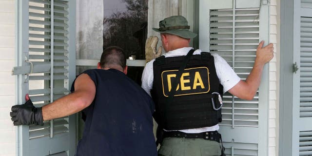 NEW ORLEANS - SEPTEMBER 10: DEA agents look into a window of a house in the while searching for victims in the Ninth Ward district September 10, 2005 in New Orleans, Louisiana. Rescue crews continue to search homes searching for hold outs and deceased people. (Photo by Justin Sullivan/Getty Images)