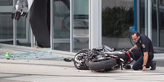 A police officer examines a motorcycle after a female stunt driver working on the movie "Deadpool 2" died after a crash on set, in Vancouver, B.C., on Aug. 14, 2017. Vancouver police say the driver was on a motorcycle when the crash occurred on the movie set on Monday morning.