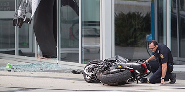 A police officer examines a motorcycle after a female stunt driver working on the movie "Deadpool 2" died after a crash on set, in Vancouver, B.C., on Aug. 14, 2017. Vancouver police say the driver was on a motorcycle when the crash occurred on the movie set on Monday morning.