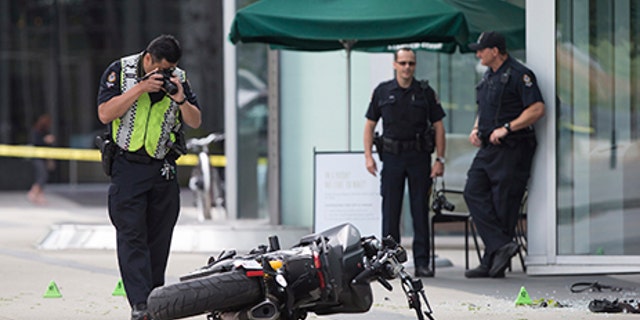 A police officer photographs a motorcycle after a female stunt driver working on the movie "Deadpool 2" died after a crash on set, in Vancouver, B.C., on Monday Aug. 14, 2017. Vancouver police say the driver was on a motorcycle when the crash occurred on the movie set on Monday morning. (Darryl Dyck/The Canadian Press via AP)