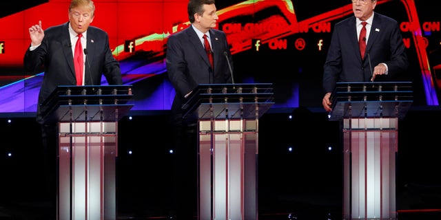 Donald Trump, a la izquierda, y Jeb Bush, a la derecha, hablan ante la mirada de Ted Cruz durante el debate republicano de CNN en el hotel y casino Venetian de Las Vegas, el martes 15 de diciembre de 2015 en Las Vegas. (AP Foto/John Locher)
