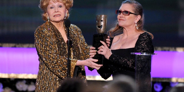 FILE- In this Jan. 25, 2015, file photo, Carrie Fisher, right, presents her mother Debbie Reynolds with the Screen Actors Guild life achievement award at the 21st annual Screen Actors Guild Awards at the Shrine Auditorium in Los Angeles. "La La Land" star Ryan Gosling thanked Reynolds at the Palm Springs Film Festival on Monday, Jan. 2, 2017, for serving as an inspiration to the cast and crew of the film. (Photo by Vince Bucci/Invision/AP, File)