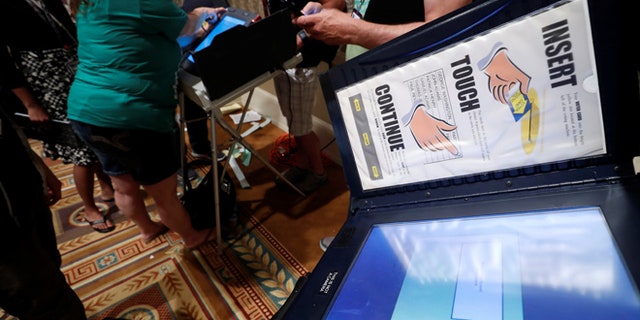 Hackers look over real voting machines in a Voting Machine Hacking Village during the Def Con hacker convention in Las Vegas, Nevada, U.S. on July 29, 2017. REUTERS/Steve Marcus - RTS19ONC