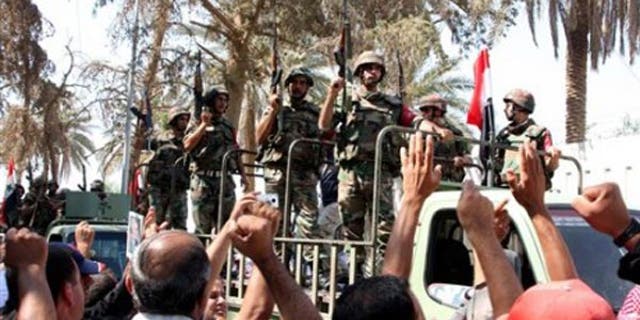 In this photo taken on a government-organized tour, residents cheer Syrian soldiers in Deir el-Zour in 2011.