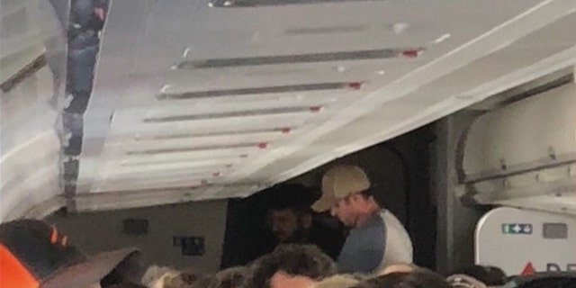 Ex-corrections officer James Tunnell (standing, wearing a tan hat) and a member of the Coast Guard sprang into action to restrain the unruly passenger.